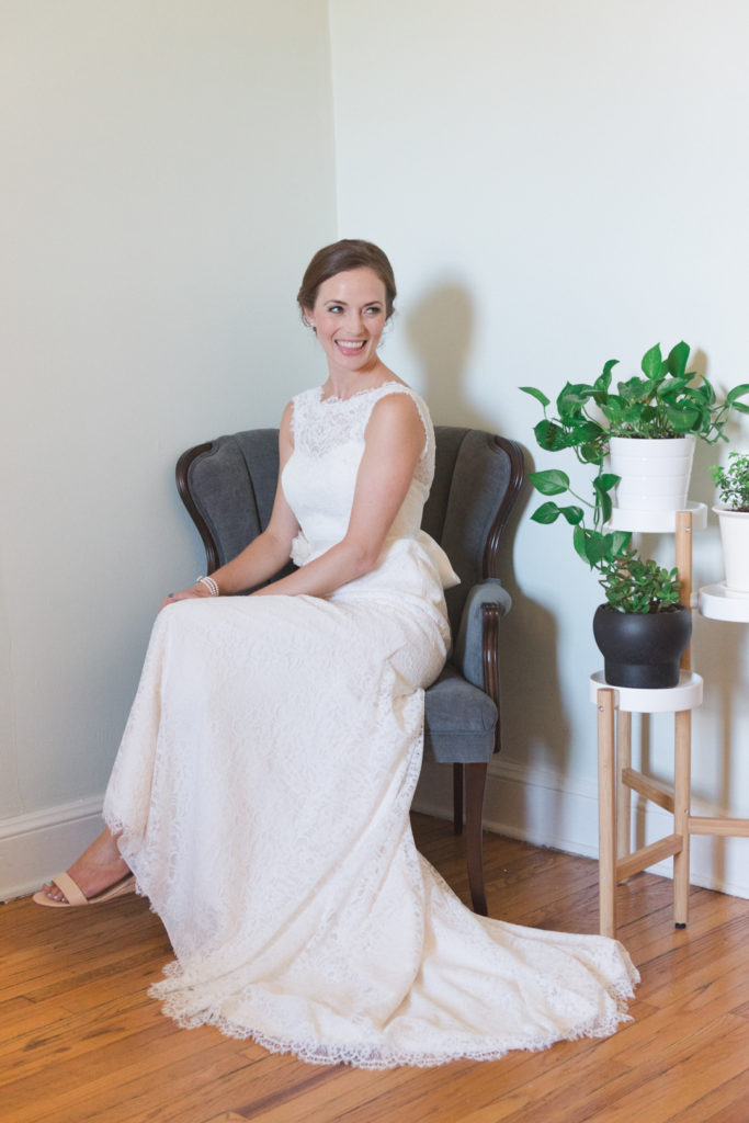 bride sitting in a vintage chair next to green plants