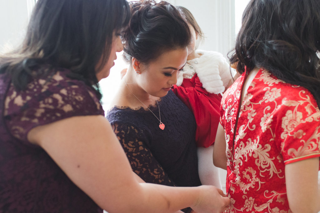 Bridesmaids helping bride into red Chinese wedding dress
