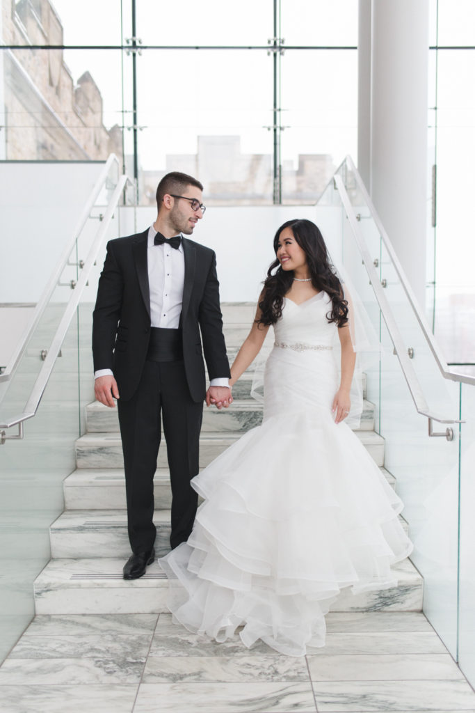 Bride and groom holding hands standing on the staircase at the Museum of Nature in Ottawa