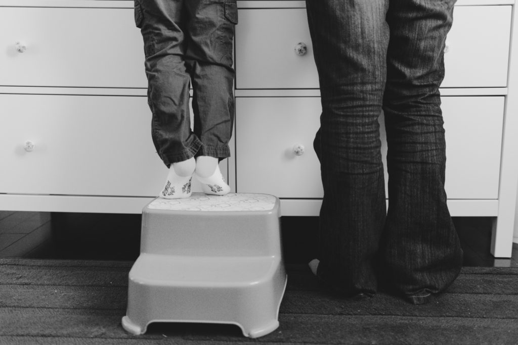 little boy on a stepping stool next to his mom