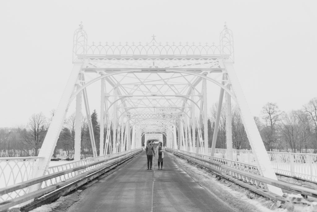 expecting parents standing on a bridge in black and white