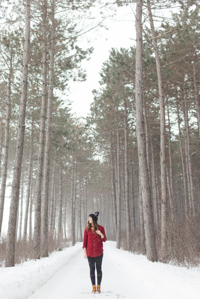 yoga instructor standing on a snow covered path among tall trees