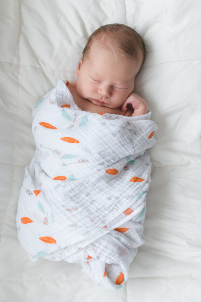 newborn baby boy wrapped in aden and anais swaddle blanket