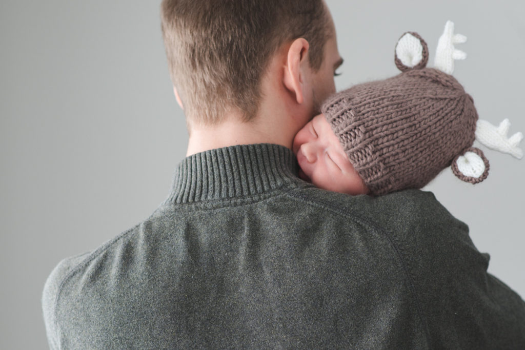 newborn baby boy cuddling with dad wearing wool reindeer hat