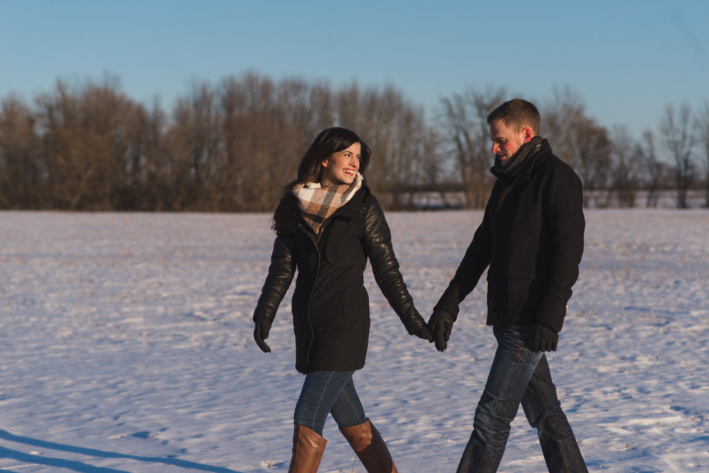 couple holding hands walking in a snowy field