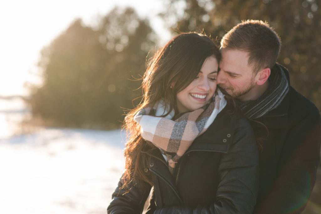 couple cuddled up at sunset in snowy field