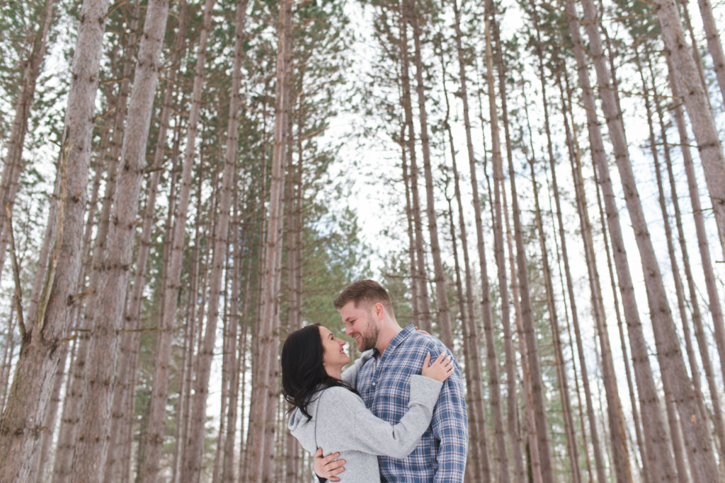 engaged couple hugging among the tall trees