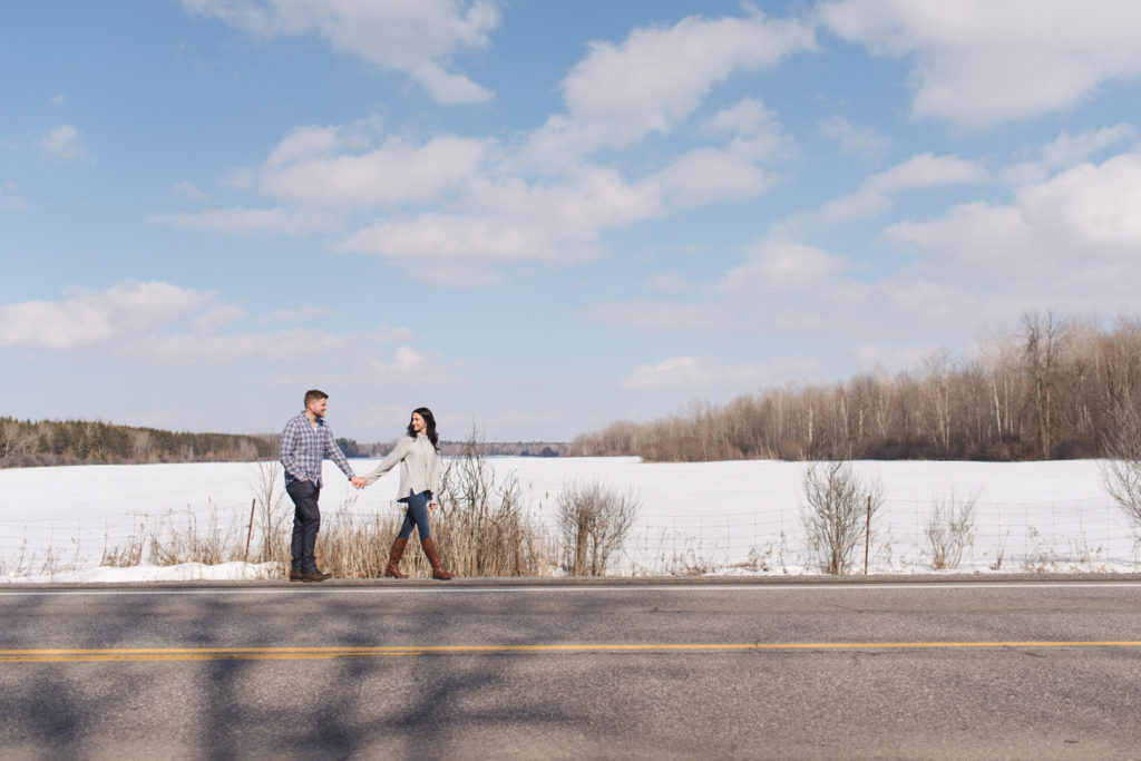 couple walking along a country road with blue skies and snowy fields