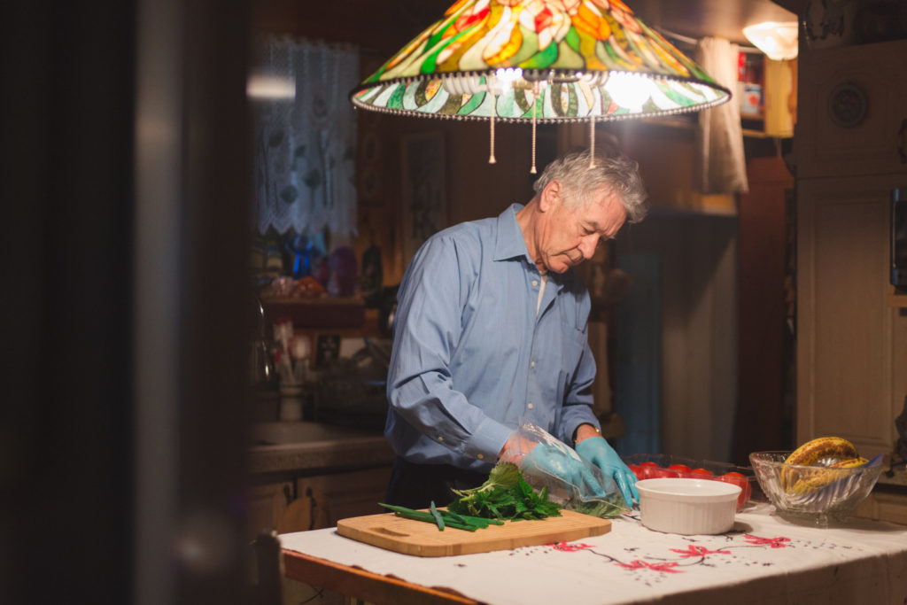 retired man cutting herbs at home for lunch