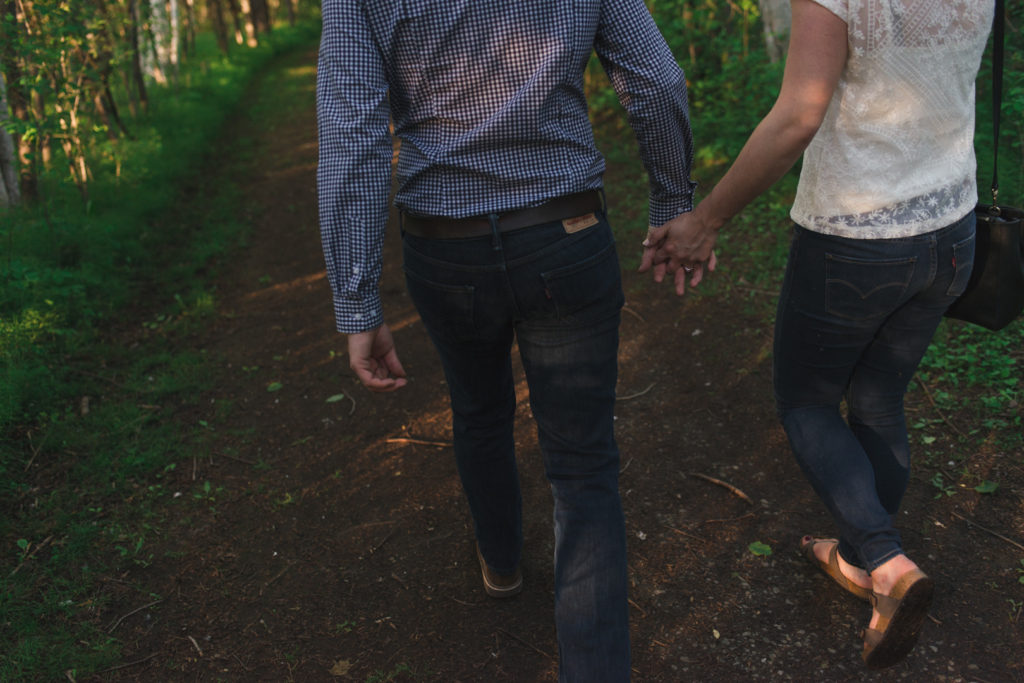 Couple holding hands walking together in the woods at sunset - Ashley Notley Photography