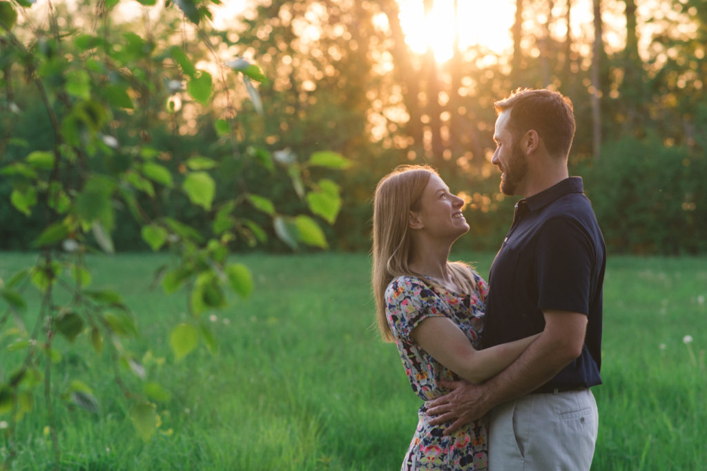 Couple smiling with each other at sunset in a field