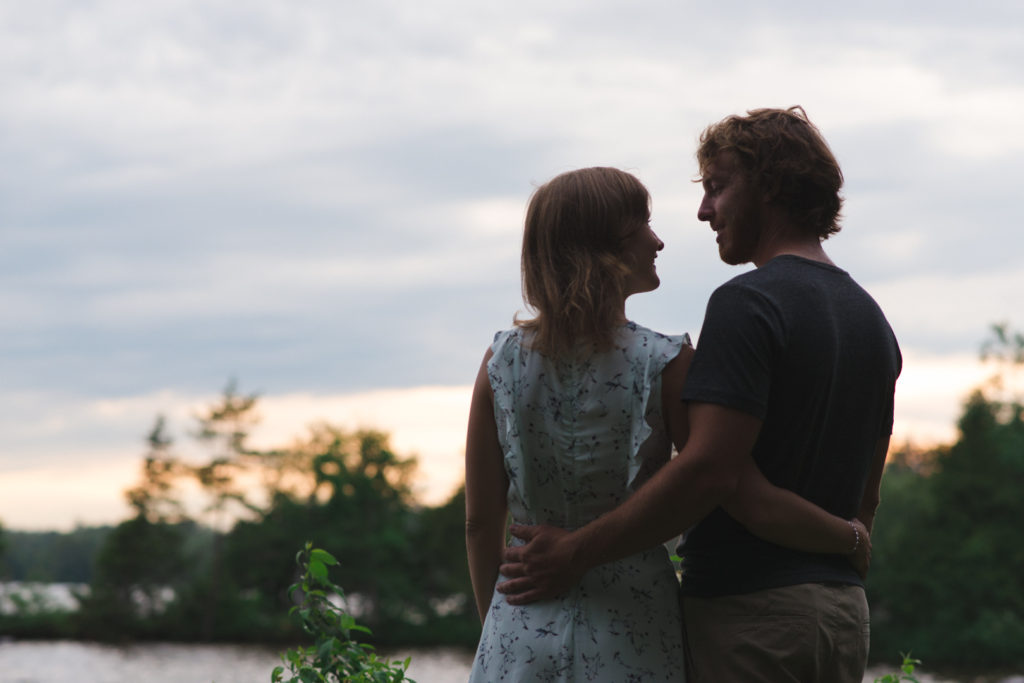 couple with arms around each other smiling at sunset