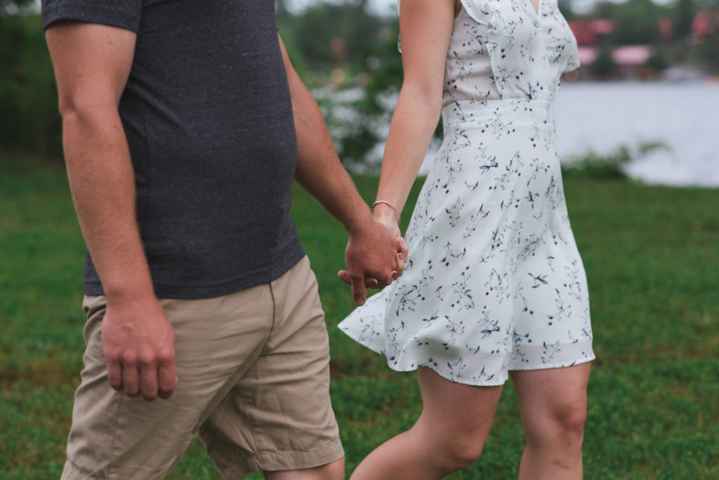 couple holding hands walking in the grass
