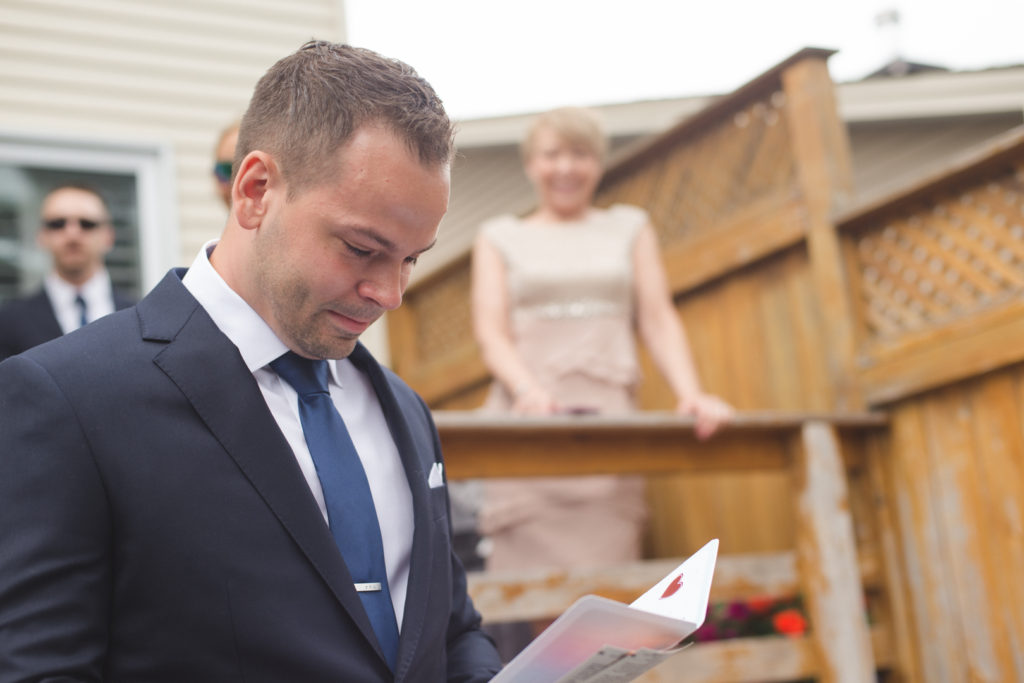 groom tearing up as he reads his card from his bride on their wedding day