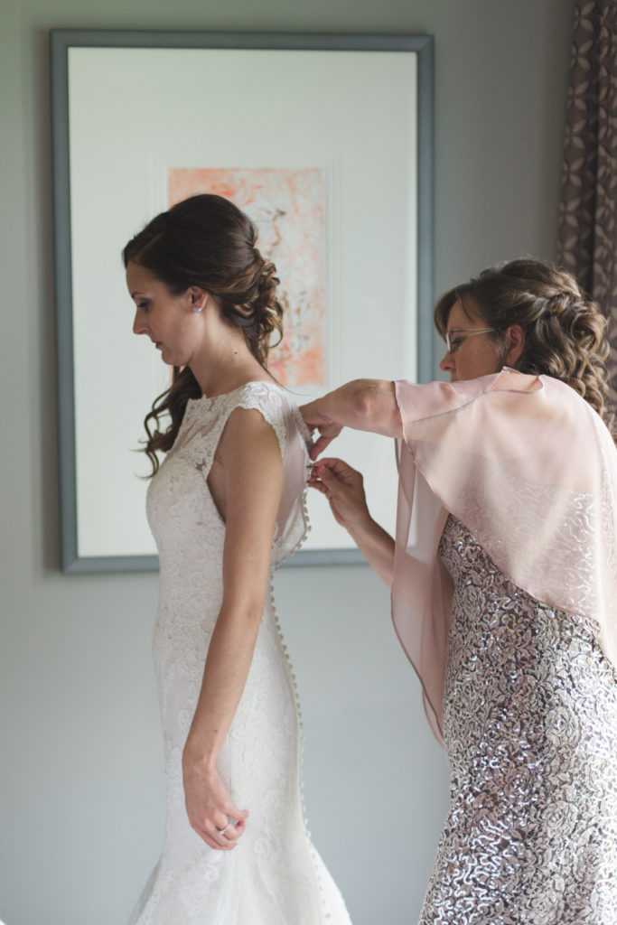 bride putting on her dress with her mother's help