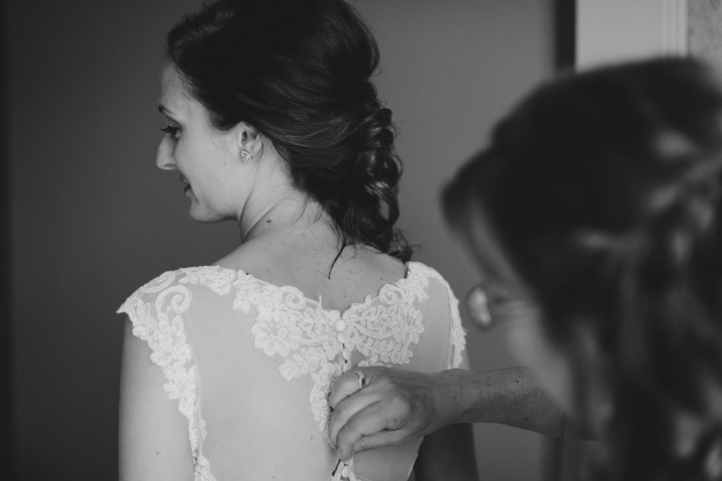 mother of bride helping her daughter into her wedding dress