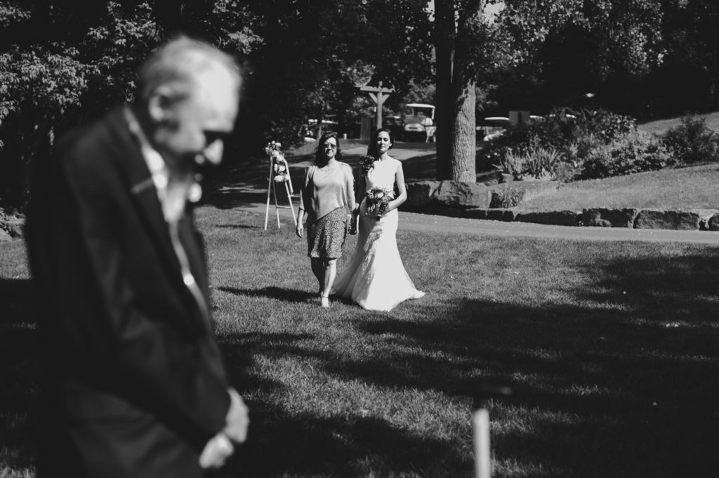 bride and her mother walking towards her father at the end of the aisle