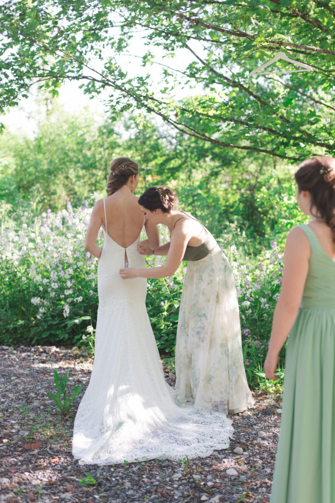 bridesmaids helping bride into her dress