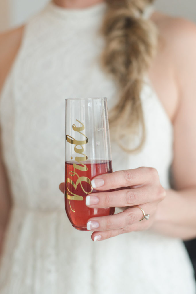 Bride to be holding a wine glass with "bride" written on it in gold
