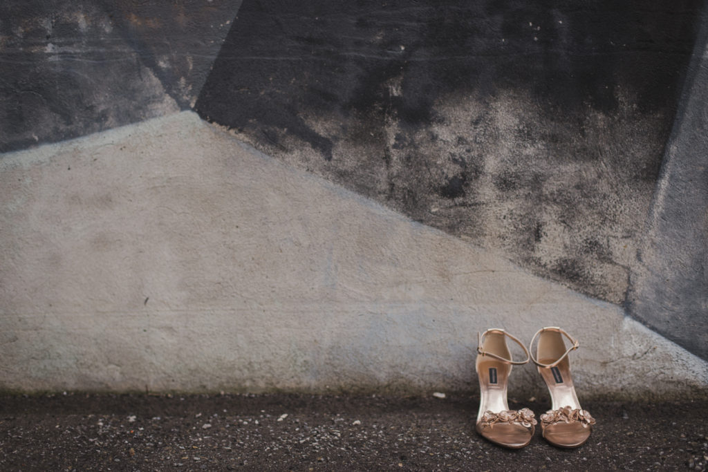 gold shoes against cement mural wall