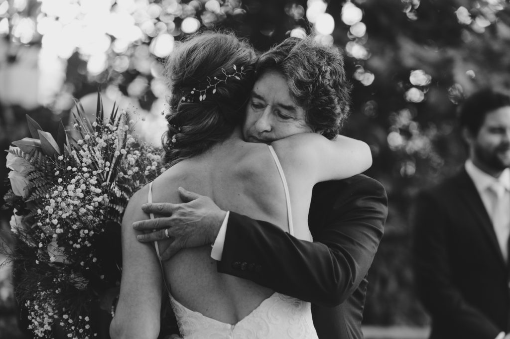 father hugging his daughter at the end of the aisle on her wedding day