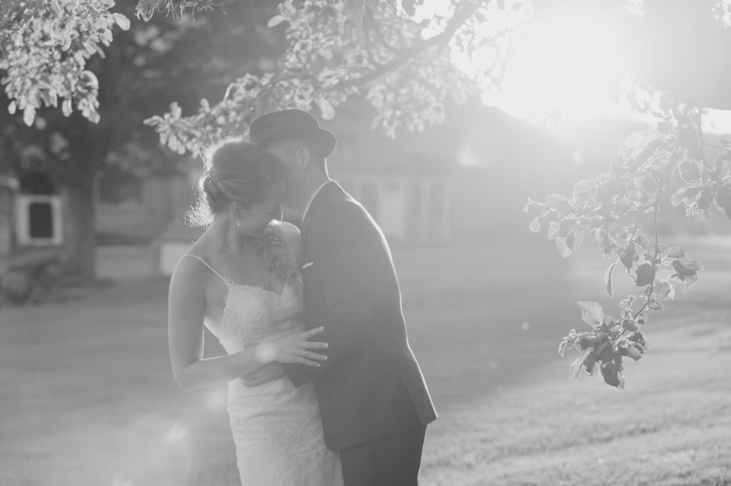 bride and groom kissing at sunset in black and white