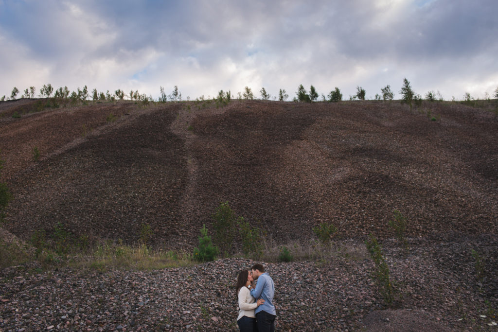 engaged couple standing at the bottom of large gravel pit of abandoned mine