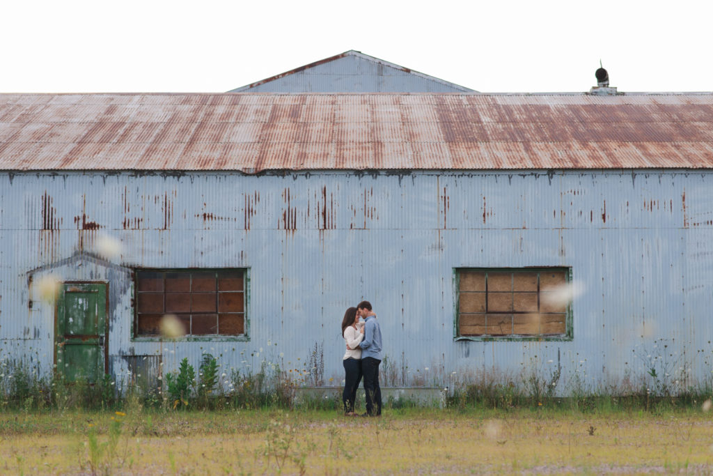 engaged couple cuddling close outside of abandoned building
