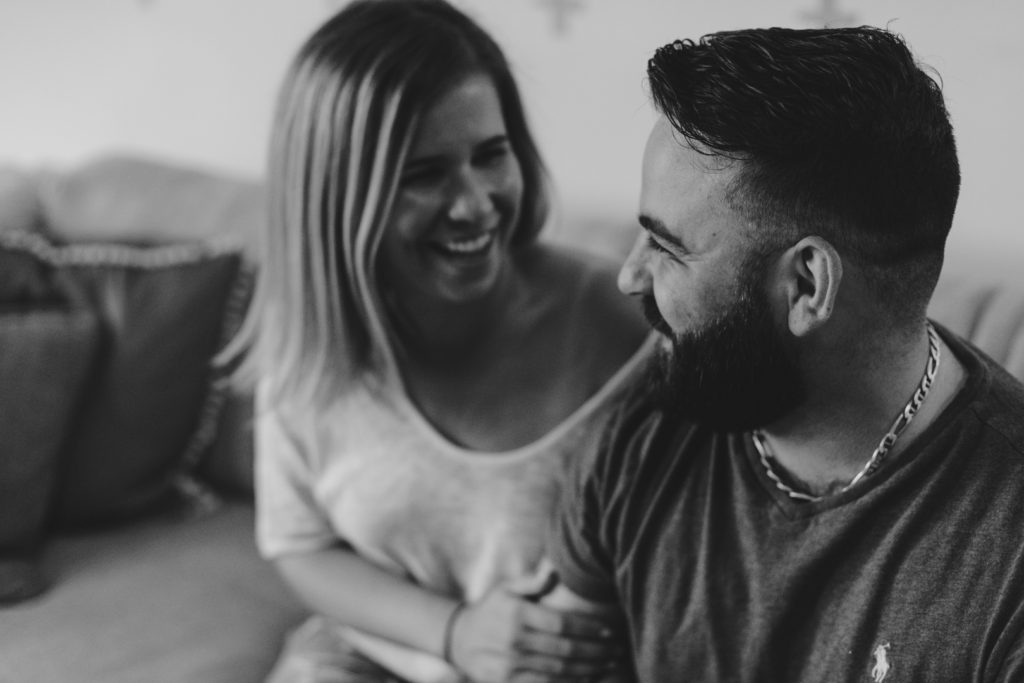 black and white photo of engaged couple cuddling on the couch