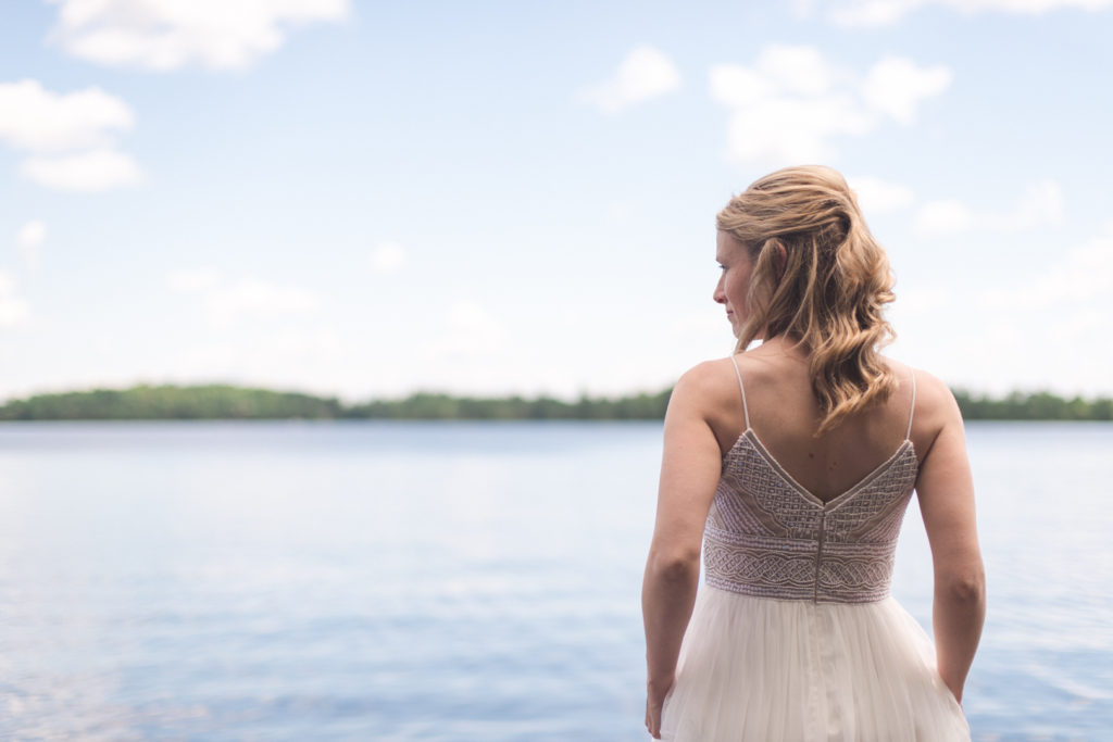 bride looking out onto the water at her family cottage by the lake