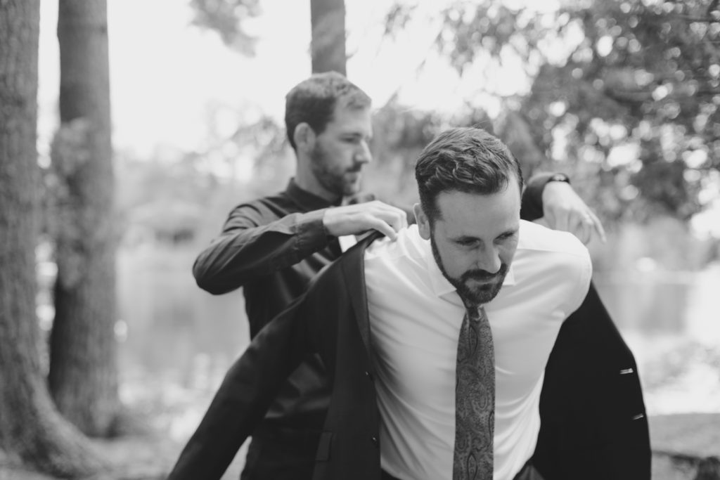 groom's brother helping the groom into his suit jacket
