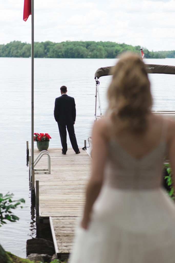 bride walking down to the dock where her groom is waiting to do a first look