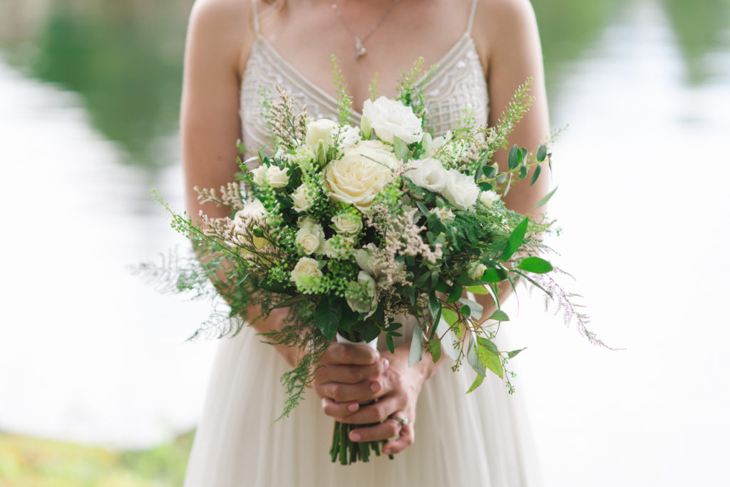 bride holding green and white wedding bouquet
