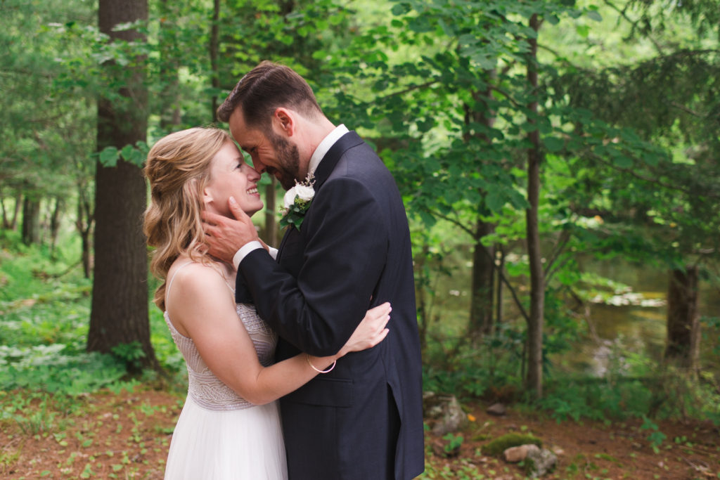 bride and groom cuddling among the trees at cottage wedding