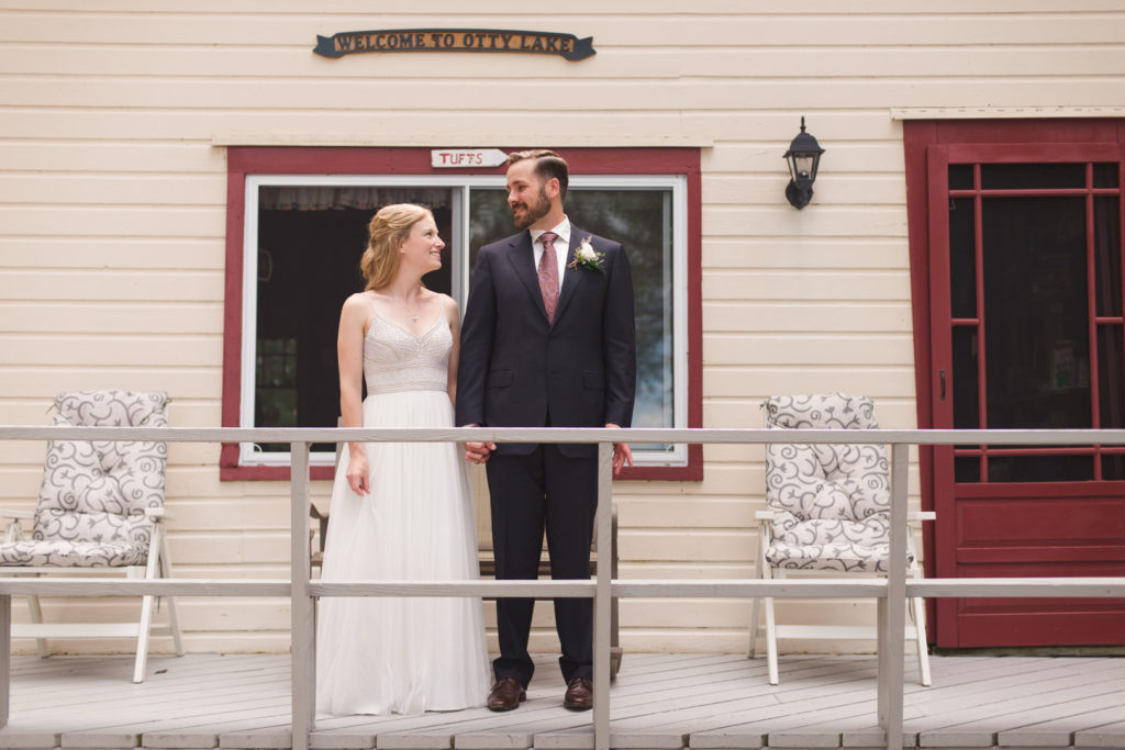 bride and groom standing on porch of cottage holding hands
