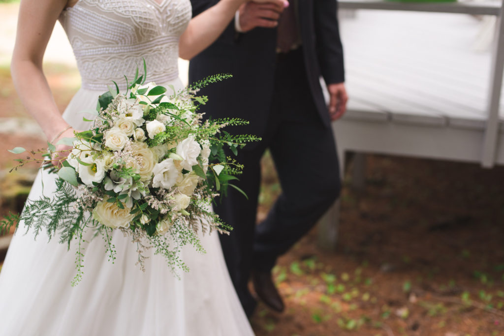 bride and groom walking around the cottage with wedding bouquet
