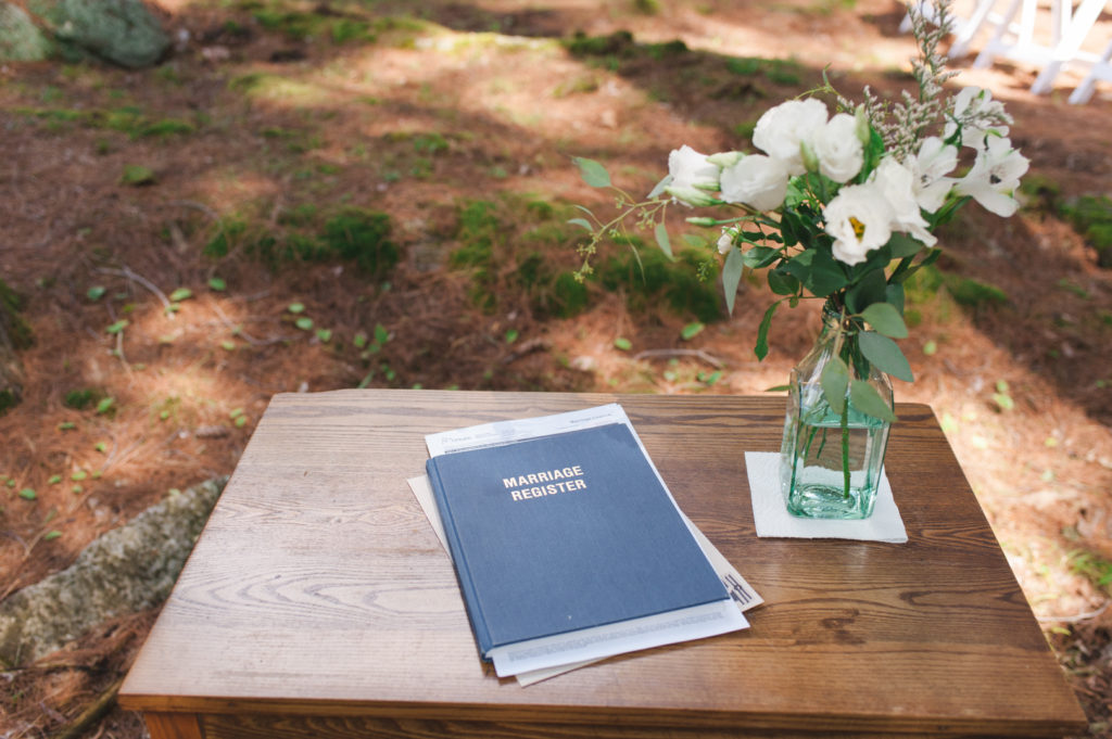 marriage register book sitting on wooden table with flowers in the forrest