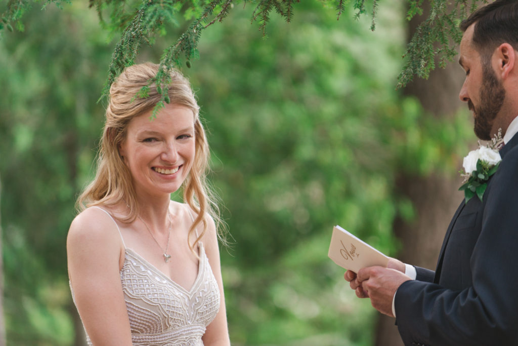 bride laughing as groom reads his vows