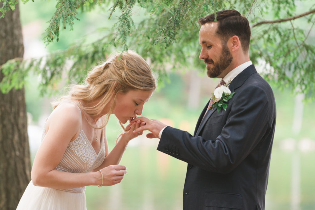 bride kissing groom's ring finger before putting on his wedding band