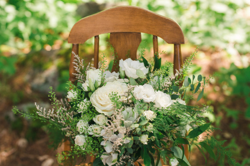 wedding bouquet sitting on wooden chair in the forrest