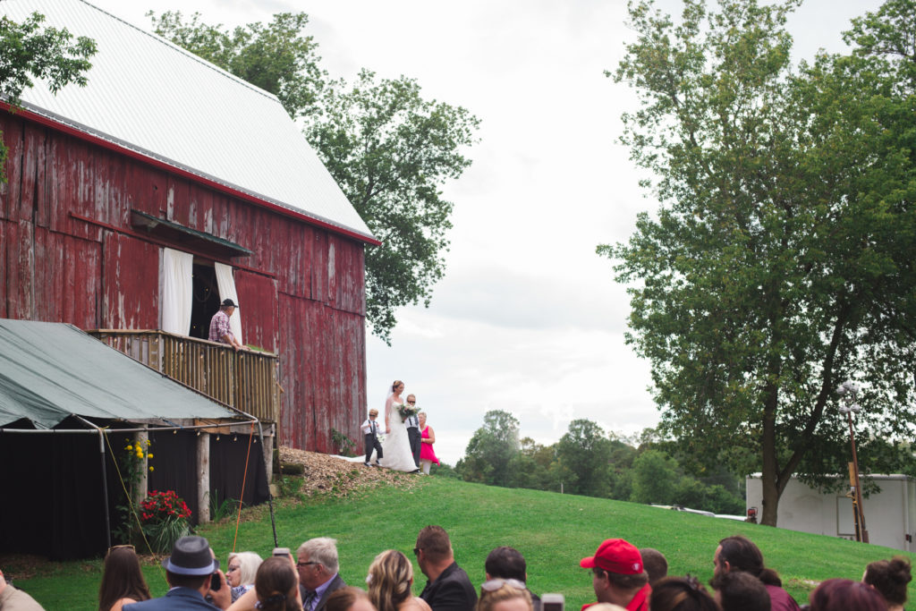bride and her sons walking out of the barn to the wedding ceremony