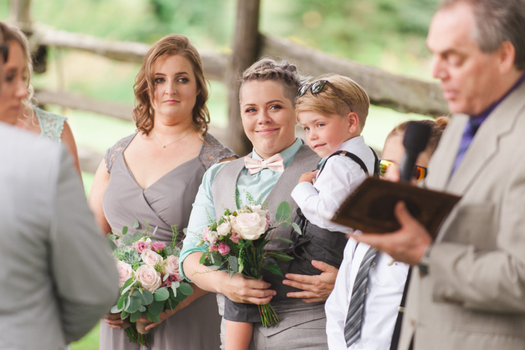 maid of honor holding the bride's son during the wedding ceremony