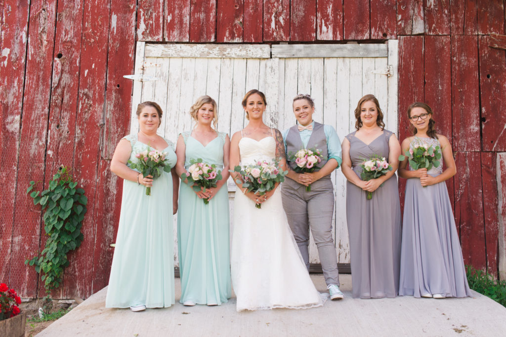bride and bridesmaids in front of red shed
