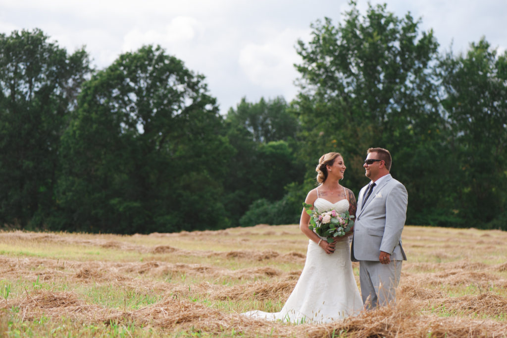 bride and groom in a field with hay