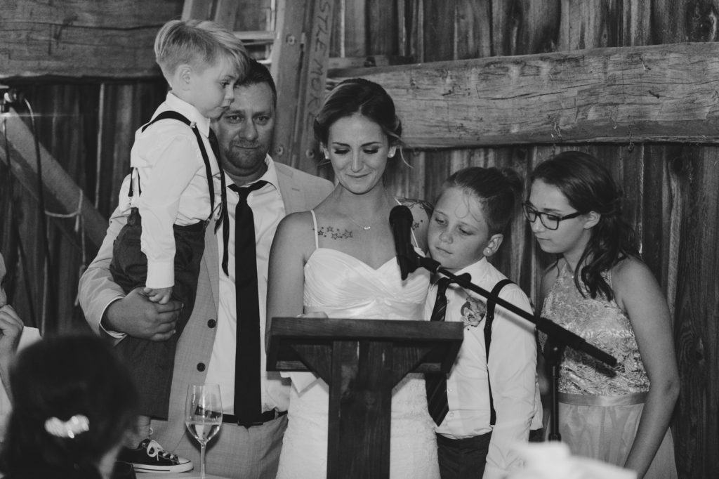 bride and groom speech with their children at the podium with them