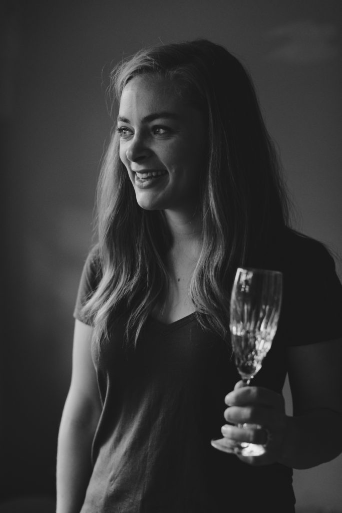 bride to be holding vintage champagne glass looking out the bedroom window