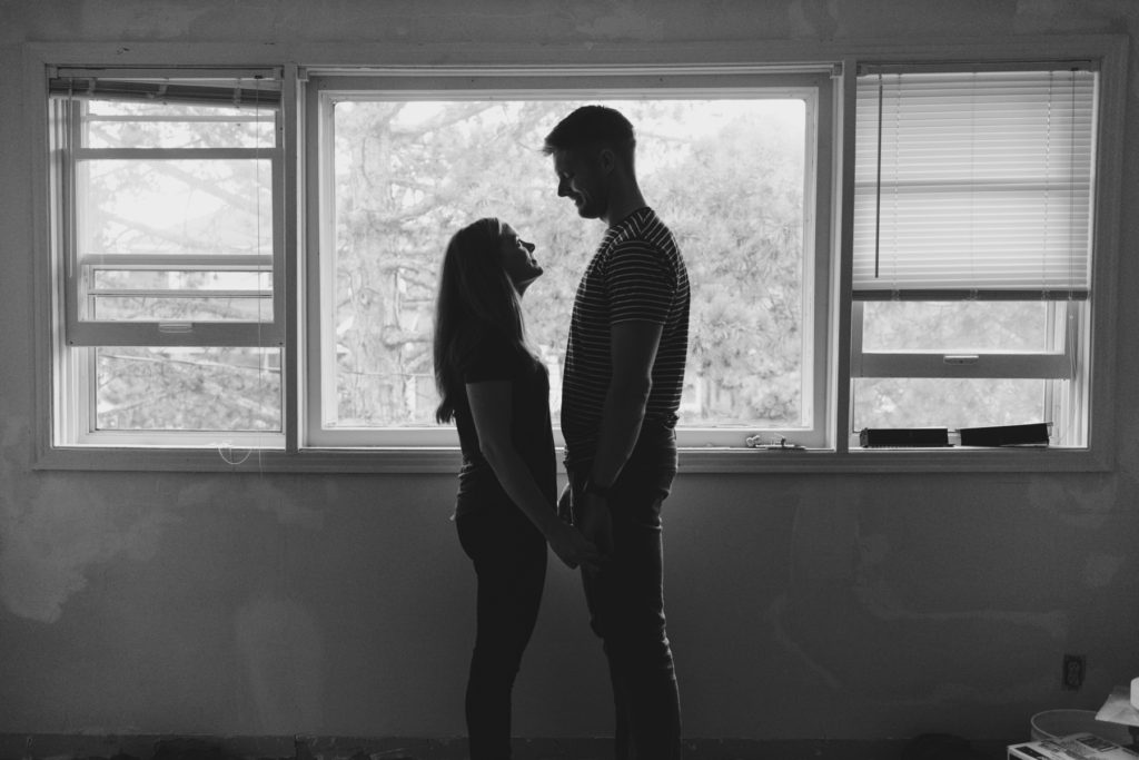 silhouette of engaged couple standing by the window in their future bedroom