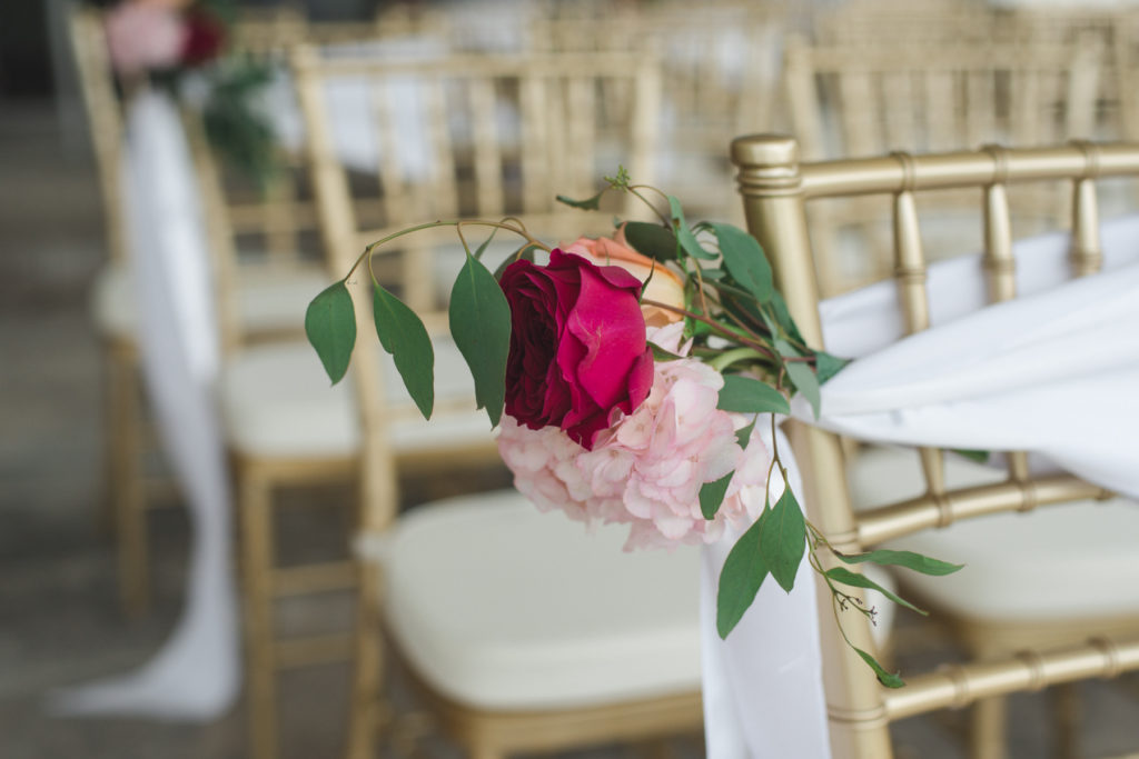 wedding florals on gold chairs at ceremony