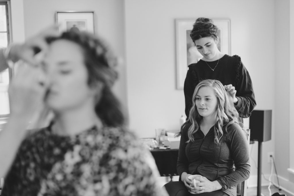 bride getting her hair done as her maid of honour gets her makeup done