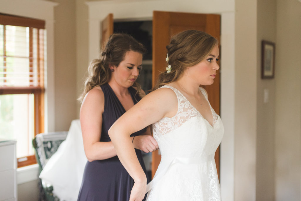 maid of honour helping the bride into her dress